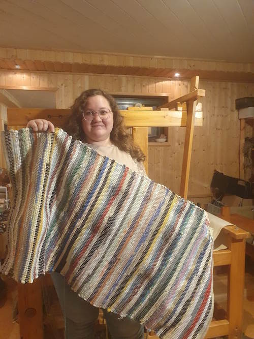 Frau mit Fleckerlteppich in de Hand 