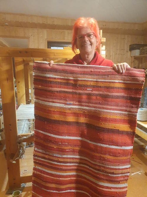 Frau mit Fleckerlteppich in de Hand