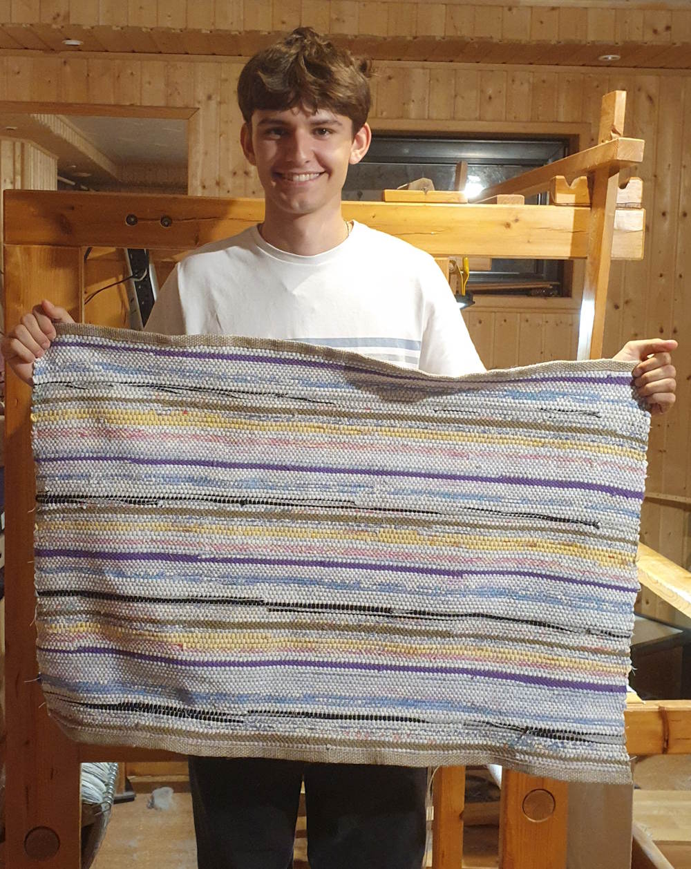 Junger Mann mit Fleckerlteppich in der Hand